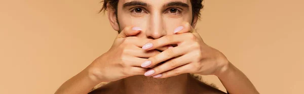 Female hands covering mouth of young man looking at camera isolated on beige, banner — Stock Photo