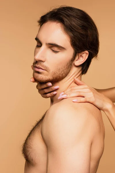 Sexy hombre con los ojos cerrados cerca de la mujer abrazando su cuello aislado en beige - foto de stock