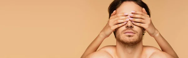 Female hands on eyes of young brunette man isolated on beige, banner — Stock Photo