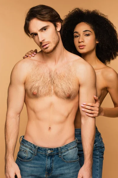 Sexy shirtless man and topless hispanic woman looking at camera isolated on beige — стоковое фото