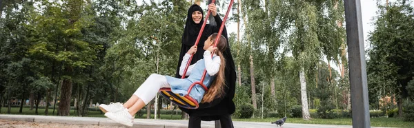 Arabe femme jouer avec fille sur swing à l'extérieur, bannière — Photo de stock