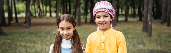 Smiling muslim kids looking at camera in park, banner — Stock Photo