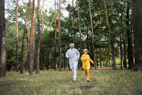 Árabe padre e hijo corriendo juntos en parque - foto de stock