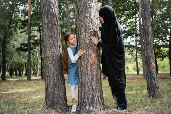 Smiling muslim mother and daughter looking at each other near tree in park — Stock Photo