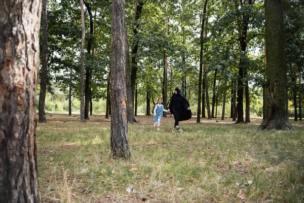 Smiling mother and muslim daughter running in park — Stock Photo