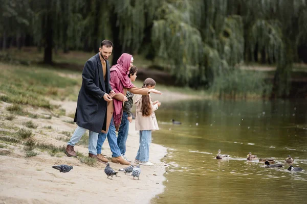 Heureuse famille musulmane regardant les oiseaux sur le lac — Photo de stock