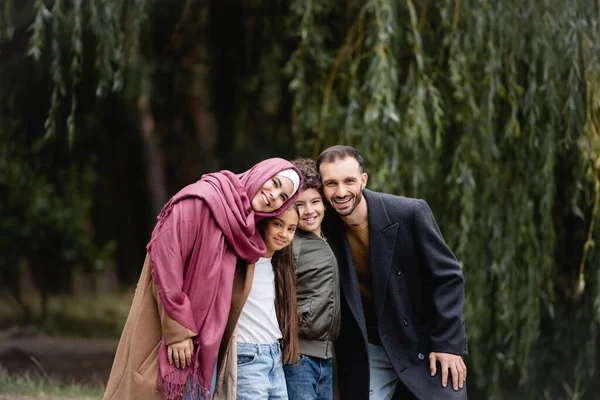 Los padres árabes sonriendo a la cámara cerca de los niños en el parque - foto de stock
