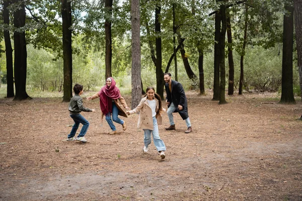 Glückliches muslimisches Mädchen spielt mit Eltern und Bruder im Park — Stockfoto