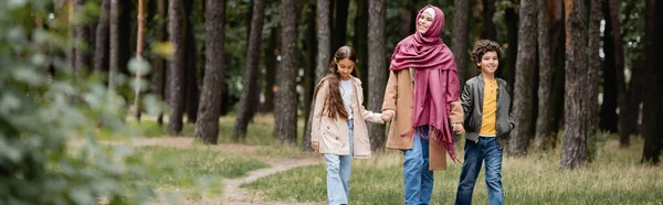 Mulher árabe no tradicional hijab andando perto de crianças no parque de outono, bandeira — Fotografia de Stock