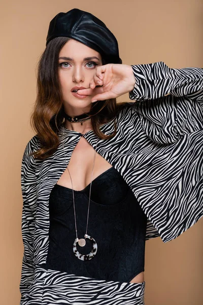 Young woman in zebra print blazer and beret looking at camera while posing isolated on beige — Stock Photo