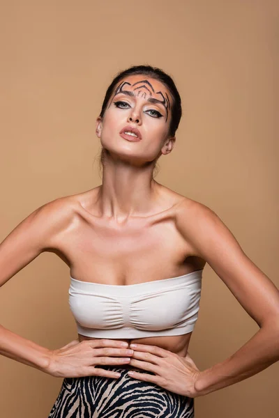Jeune femme brune aux épaules nues et au maquillage de tigre posant isolée sur beige — Photo de stock