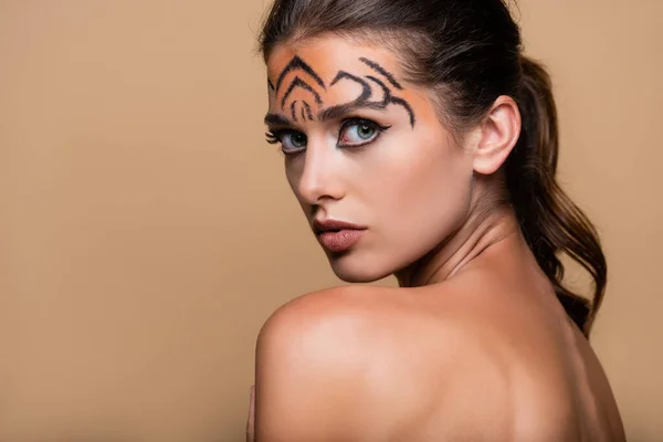 Junges und hübsches Model mit Tiger-Make-up, das isoliert auf Beige in die Kamera blickt — Stockfoto