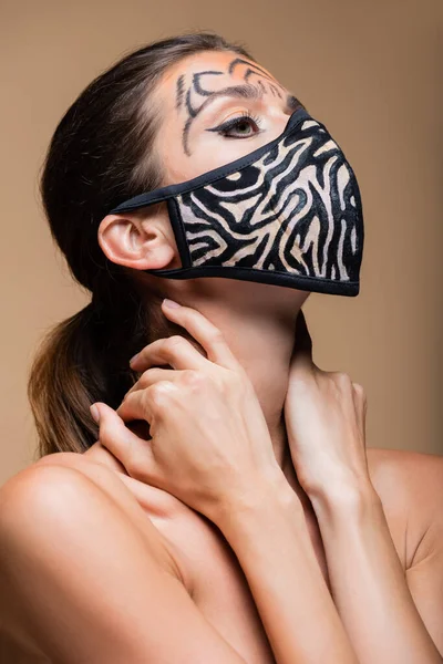 Donna con trucco tigre e maschera stampa animale posa isolata su beige — Foto stock