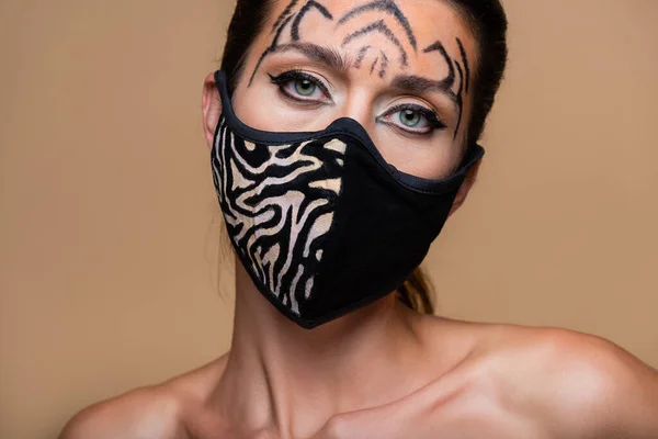 Junges Model mit Tiger-Make-up und Animal-Print-Maske schaut isoliert auf beige — Stockfoto