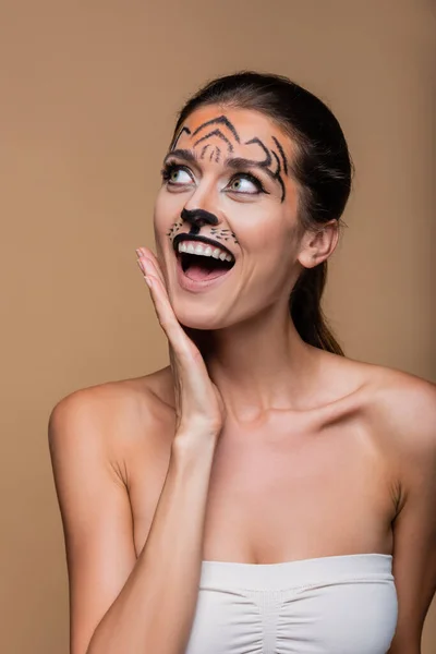 Збуджена жінка з голими плечима і тигровим макіяжем позує ізольовано на бежевому — стокове фото