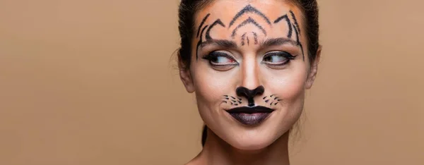 Кумедна жінка з тигровим макіяжем, що дивиться геть ізольовано на бежевому, банер — стокове фото
