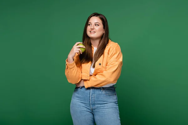 Smiling woman with overweight holding apple isolated on green — Stock Photo