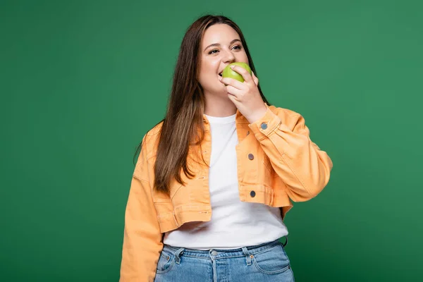 Junge Frau mit Übergewicht isst Apfel isoliert auf Grün — Stockfoto