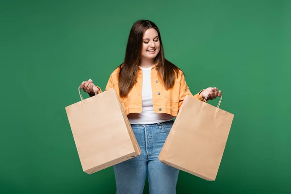 Smiling woman with overweight holding shopping bags isolated on green — Stock Photo