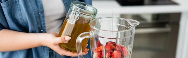 Cropped view of plus size woman pouring honey in blender with strawberries, banner — Stock Photo