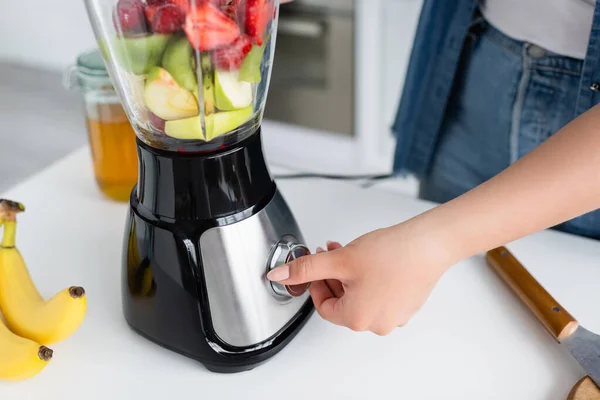 Vue recadrée du mélangeur de commutation femme taille plus pendant la cuisson smoothie dans la cuisine — Photo de stock