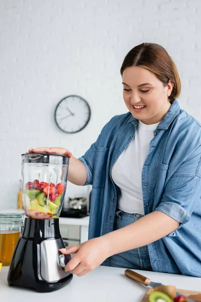 Mulher alegre com excesso de peso fazendo smoothie perto de mel na cozinha — Fotografia de Stock