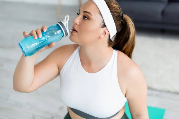 Sportswoman with overweight drinking water at home — Stock Photo