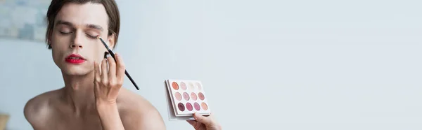 Maquillador aplicando sombra de ojos sobre hombre transgénero, banner - foto de stock