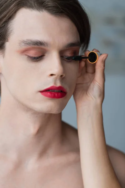 Maquillador aplicando rímel a hombre transgénero - foto de stock