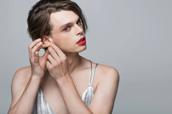 Giovane transgender uomo toccare orecchio isolato su grigio — Foto stock