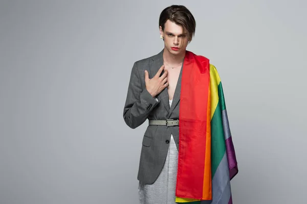 Молодий транссексуальний чоловік в блазень і плаття ковзання тримає lgbt прапор ізольовані на сірому — стокове фото