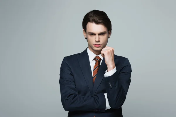 Young businessman in suit looking at camera isolated on grey — Stock Photo