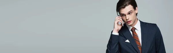 Jovem empresário de terno falando em smartphone isolado em cinza, banner — Fotografia de Stock