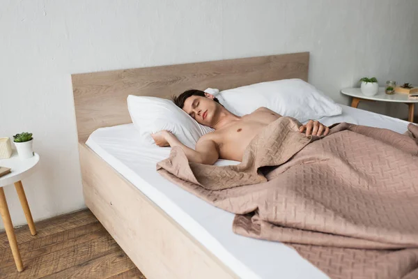 Sin camisa hombre transgénero durmiendo en la cama en casa - foto de stock