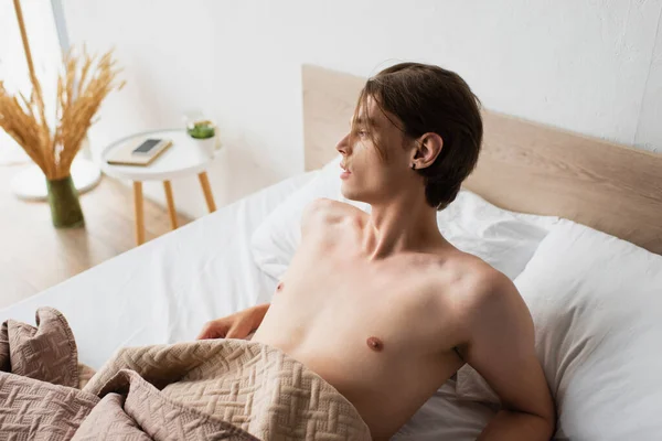Acordada e sem camisa jovem transexual homem no quarto — Fotografia de Stock