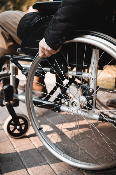 Обрізаний вид на старшого чоловіка, який сидить у інвалідному візку на відкритому повітрі — стокове фото