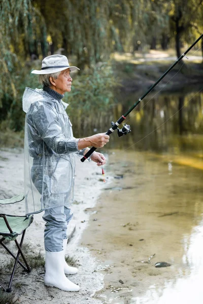 Боковой вид мужчины, рыбачившего у озера осенью — стоковое фото