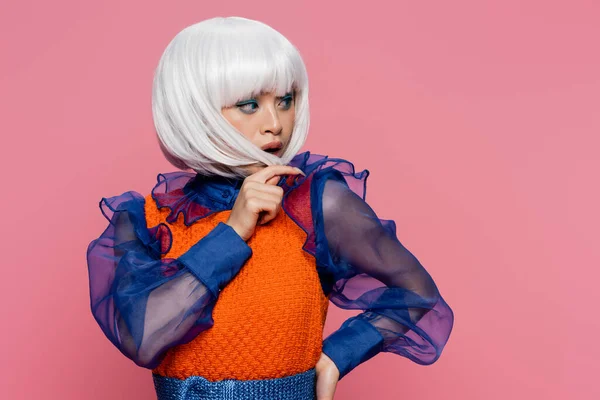 Pretty asian pop art woman touching hair of white wig isolated on pink — Stock Photo