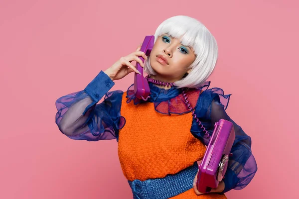 Bastante asiático pop arte modelo envuelto en cable hablando por teléfono aislado en rosa - foto de stock