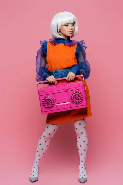 Trendy asiatische Frau im Vintage-Kleid hält Boombox auf rosa Hintergrund — Stockfoto