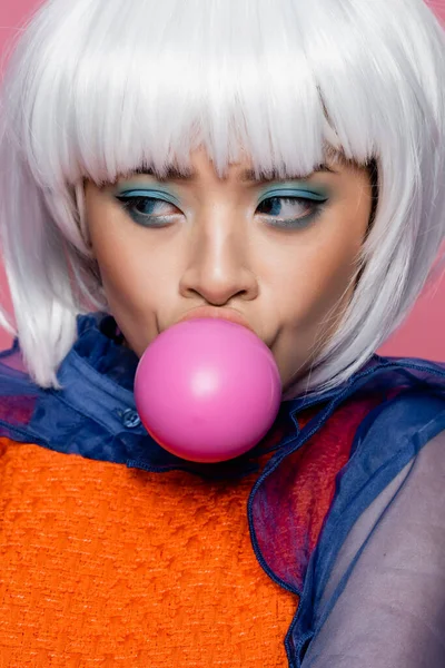 Portrait of asian pop art model in white wig blowing bubble gum isolated on pink — Stock Photo