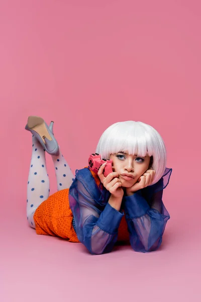 KYIV, UKRAINE - 10 DÉCEMBRE 2020 : Modèle pop art asiatique pensif tenant un joystick sur fond rose — Photo de stock