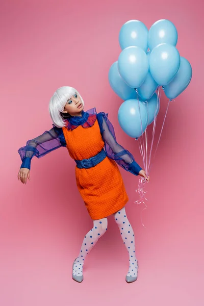 Asiatisches Pop-Art-Modell mit blauen Luftballons auf rosa Hintergrund — Stockfoto