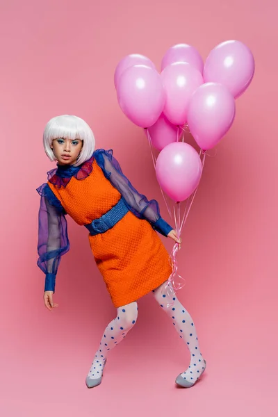 Asian pop art model in vintage dress holding balloons on pink background — Stock Photo