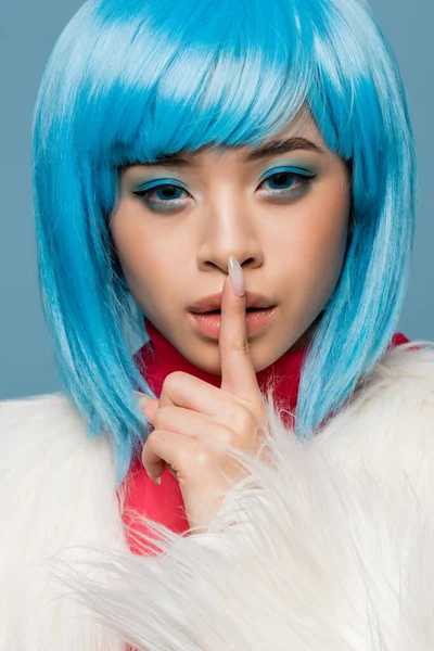 Ritratto di modello pop art asiatico in giacca pelosa che mostra il gesto shh isolato sul blu — Foto stock