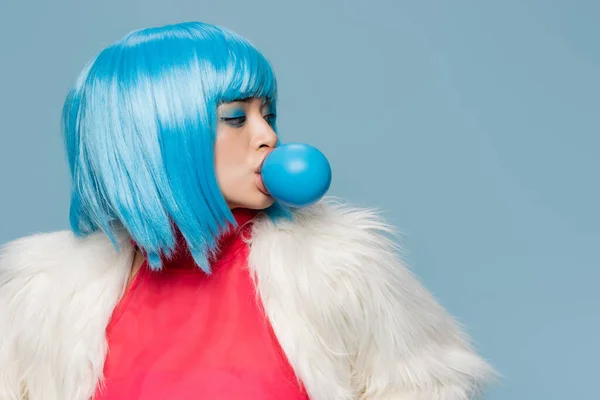 Fashionable asian woman blowing bubble gum isolated on blue — Stock Photo