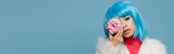 Stilvolle asiatische Frau hält Donut mit Glasur nahe Gesicht isoliert auf blau, Banner — Stockfoto