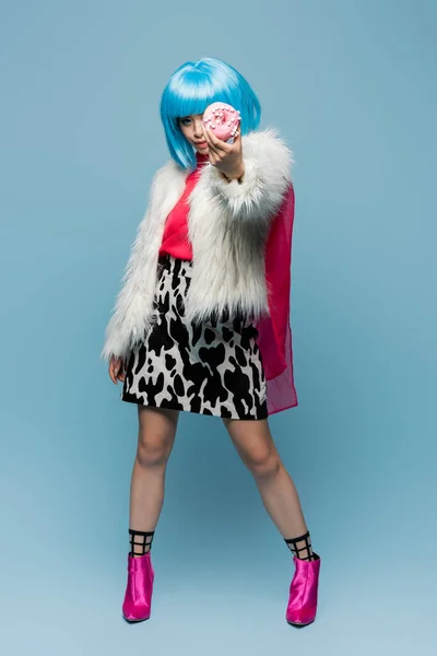 Повна довжина стильної азіатської поп-арт жінки, що показує пончик на синьому фоні — стокове фото
