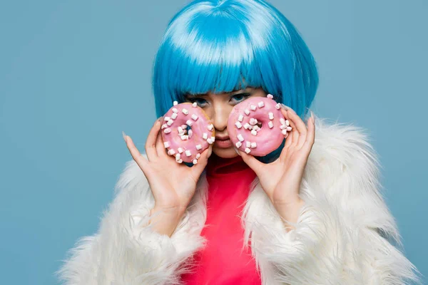 Asian pop art woman holding tasty donuts near face isolated on blue — Stock Photo