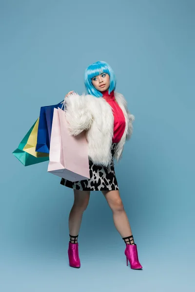 Asiatico pop art donna holding shopping bags e guardando lontano su sfondo blu — Foto stock